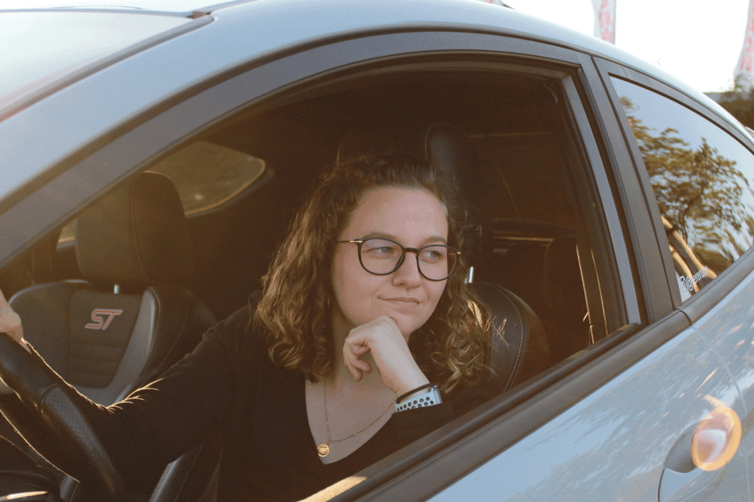 Woman smiling while sitting in the driver's seat of her car