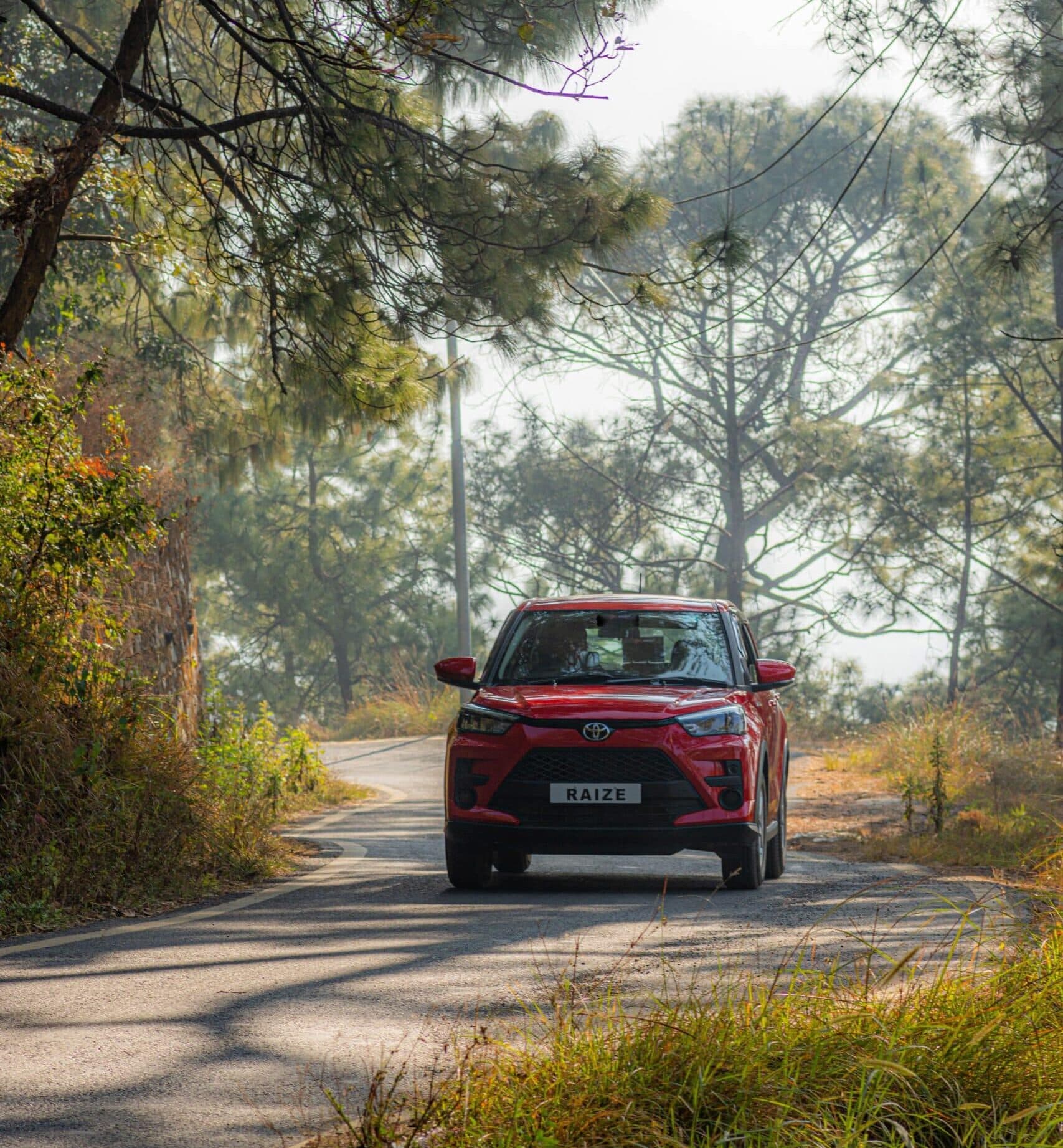 Red SUV driving along a tree-lined country road