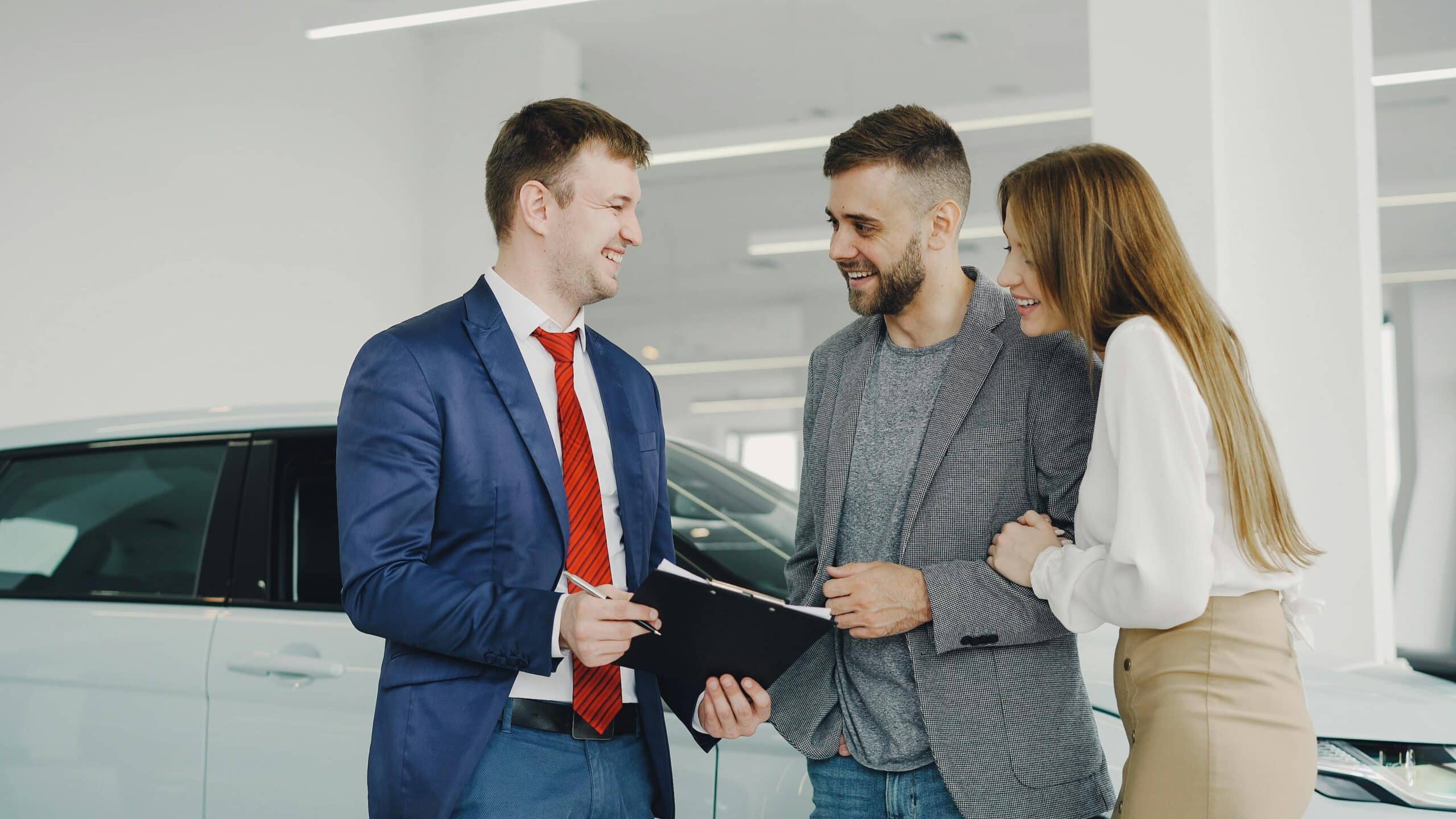 couple happy and speaking to a car salesman with clipboard