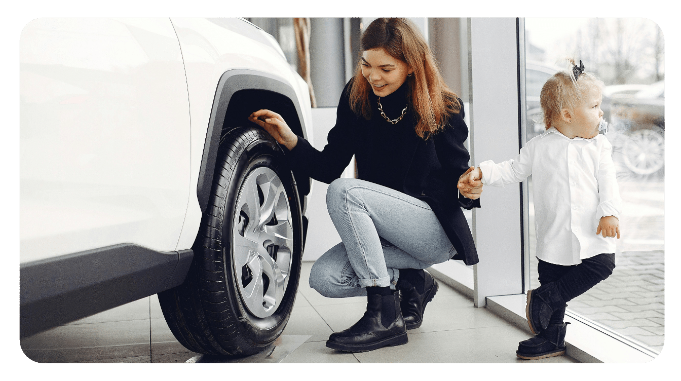 woman with child in showroom inspecting a white car